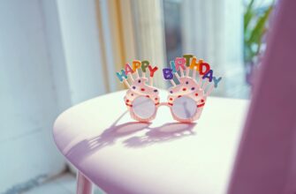 привітання з днем народження свекрусі — Colorful birthday glasses with 'Happy Birthday' sign on a pink chair in bright sunlight. | ITmaxService