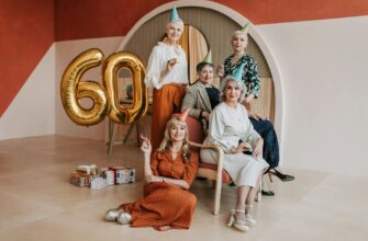 Щирі привітання з ювілеєм жінці — Five senior women celebrating a 60th birthday with party hats and balloons indoors. | ITmaxService