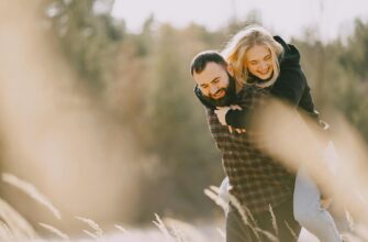привітання коханому з днем народження — Positive piggyback couple in warm casual wear hugging and having fun while spending weekend together in countryside in sunny morning | ITmaxService